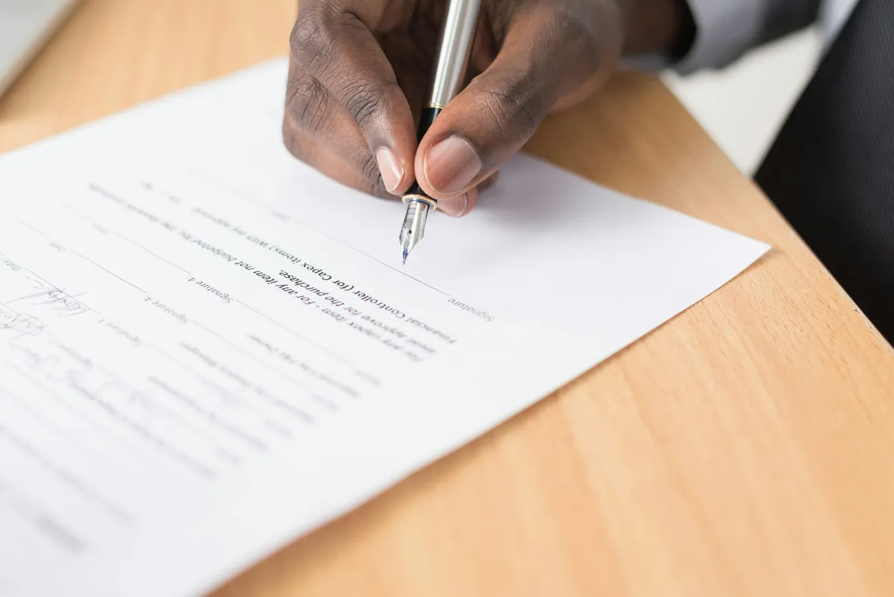 A professional signing a document at a wooden desk