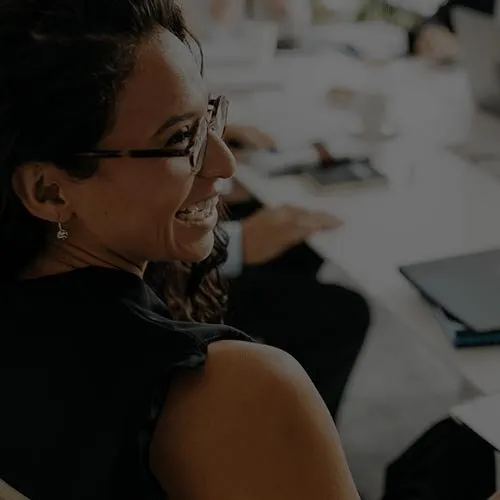 A smiling woman with glasses in a meeting