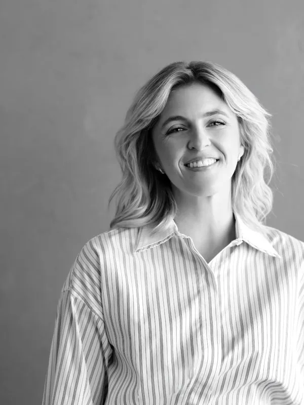 Black and white portrait of Aryn Abbot, President of Riverbend Appraisals, smiling in a striped shirt